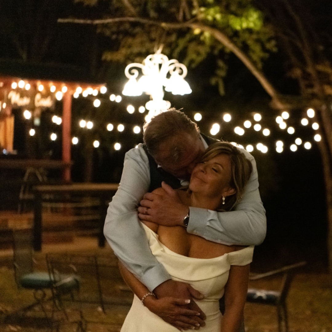 bride and groom embracing under string lights
