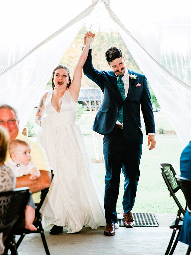 bride and groom holding hands entering wedding reception